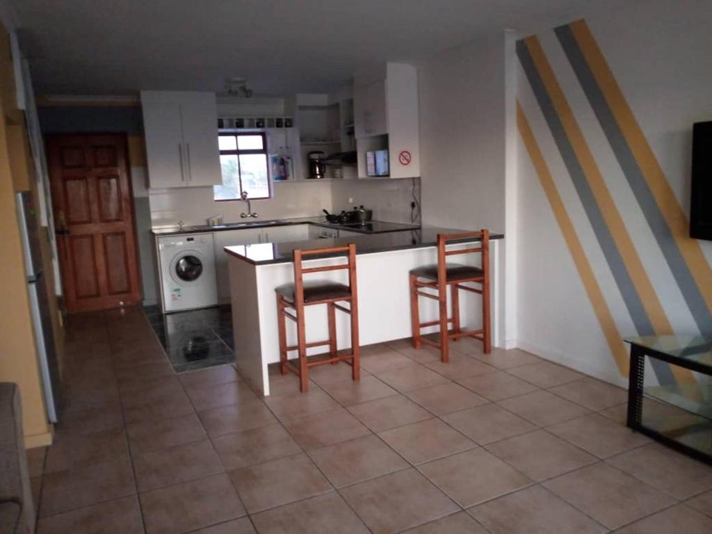 a kitchen with two bar stools and a counter top at Gabby's apartment in Cape Town