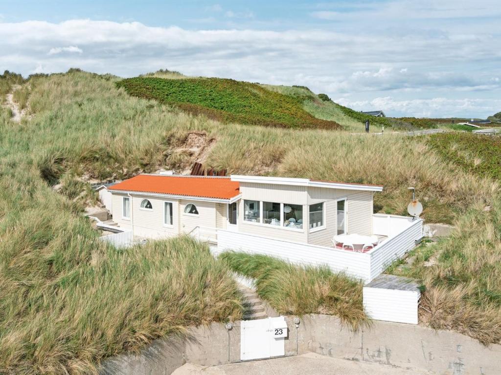 洛肯的住宿－Holiday Home Franja - 100m from the sea in NW Jutland by Interhome，沙子上有一个橙色屋顶的白色房子