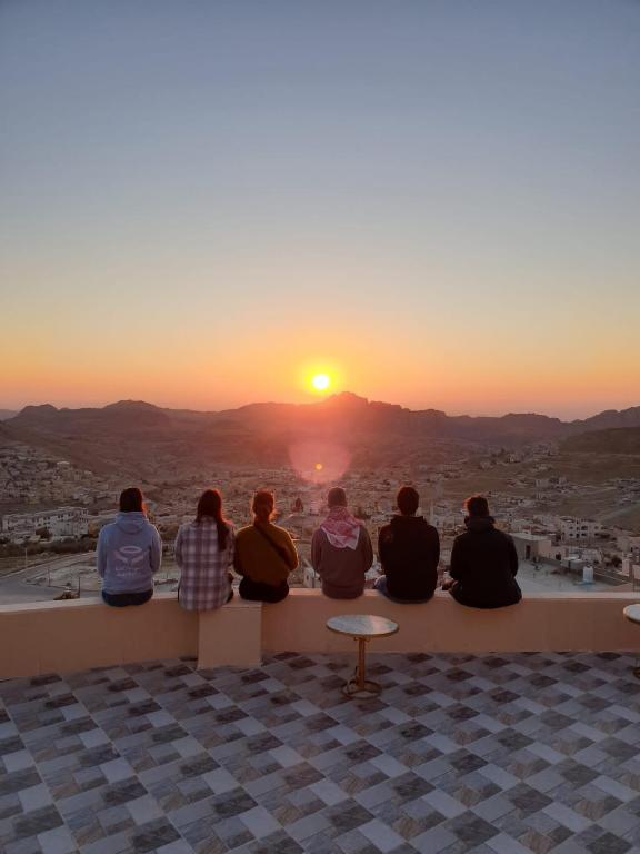 a group of people sitting on a ledge watching the sunset at Cozy House in Wadi Musa