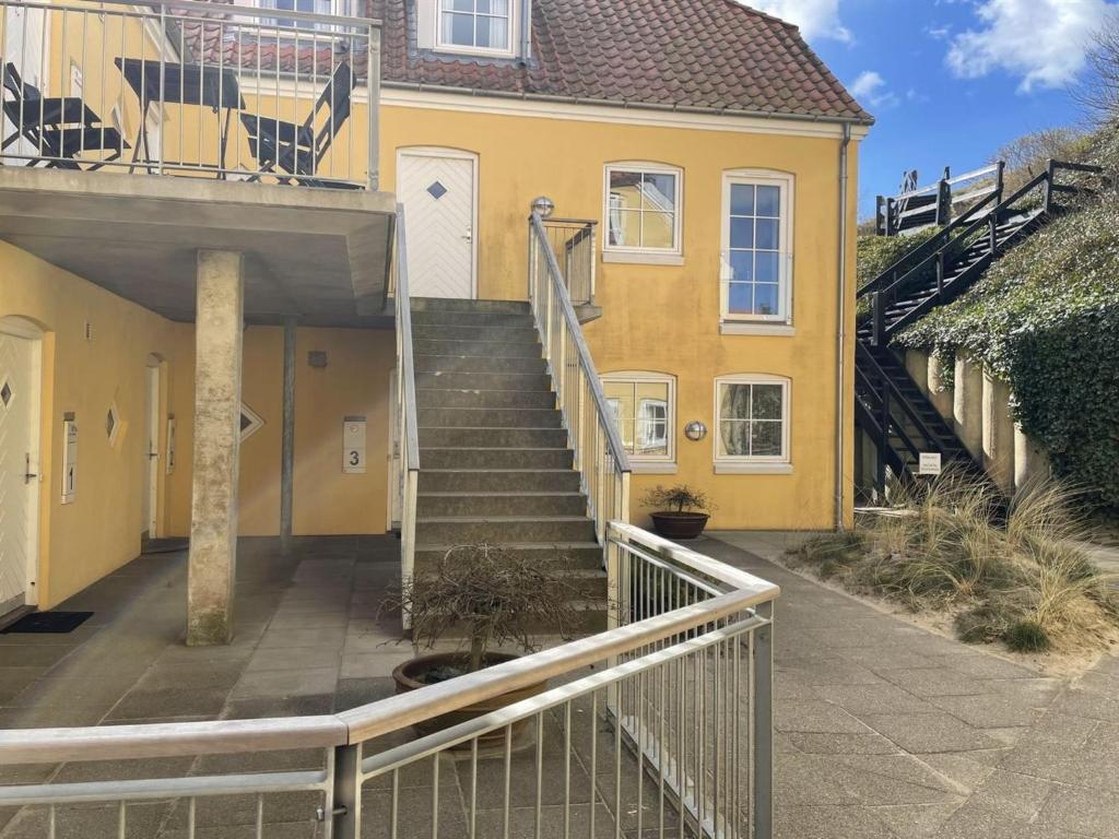a staircase leading to a yellow house with a stair railing at Apartment Almar - 400m from the sea in NW Jutland by Interhome in Hjørring