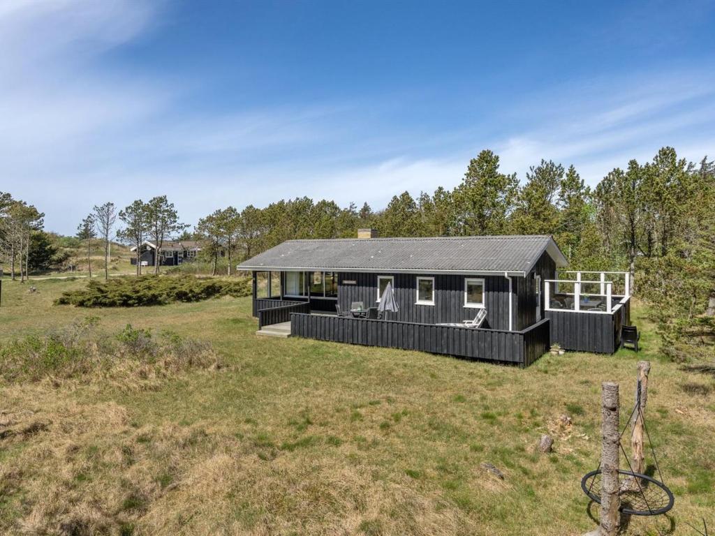 a black house in a field with a yard at Holiday Home Melisande - 950m from the sea in NW Jutland by Interhome in Saltum