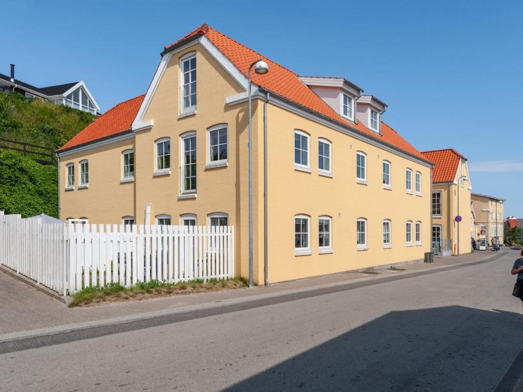 una casa amarilla con techo naranja y valla blanca en Apartment Cornel - 400m from the sea in NW Jutland by Interhome, en Hjørring