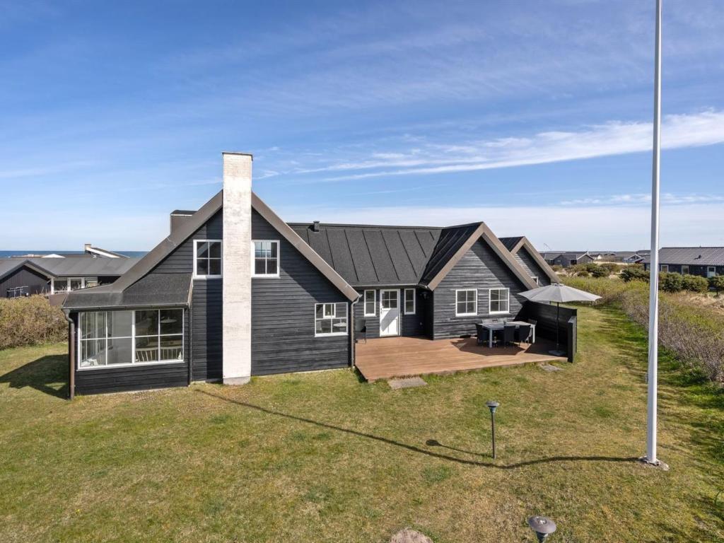 une maison noire avec une grande cour dans l'établissement Holiday Home Galin - 200m from the sea in NW Jutland by Interhome, à Hjørring