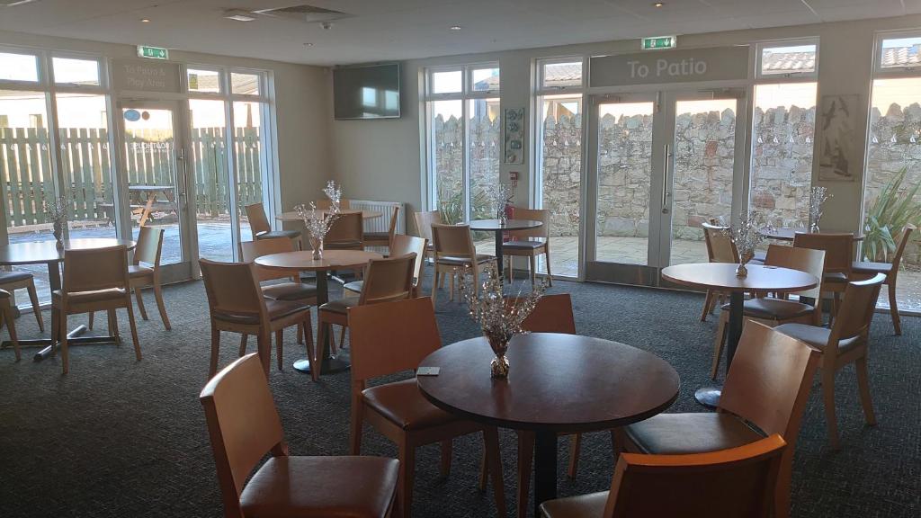 a dining room with tables and chairs and windows at Your Holidays in Scotland. in Eyemouth