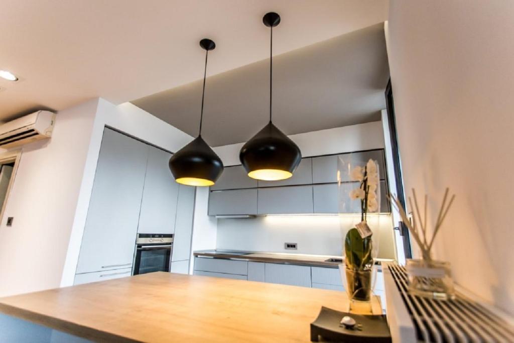 a kitchen with two pendant lights and a wooden table at Anvers Apartament in Bucharest