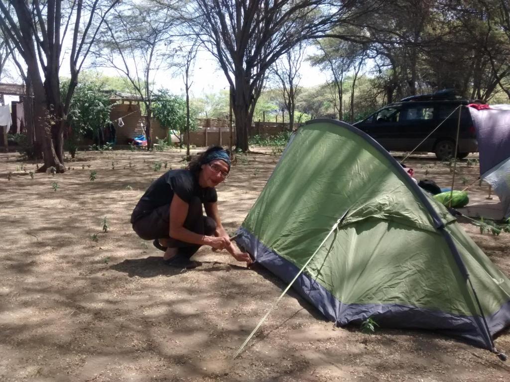 een vrouw die een tent in een veld zet bij Camping Matufa Mancora in Canoas De Punta Sal
