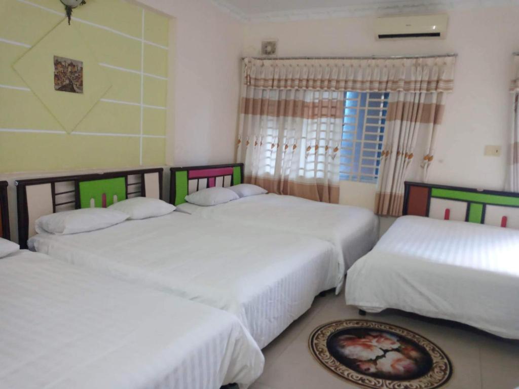 a bedroom with three beds and a window at Motel Thanh Huyền in Vung Tau