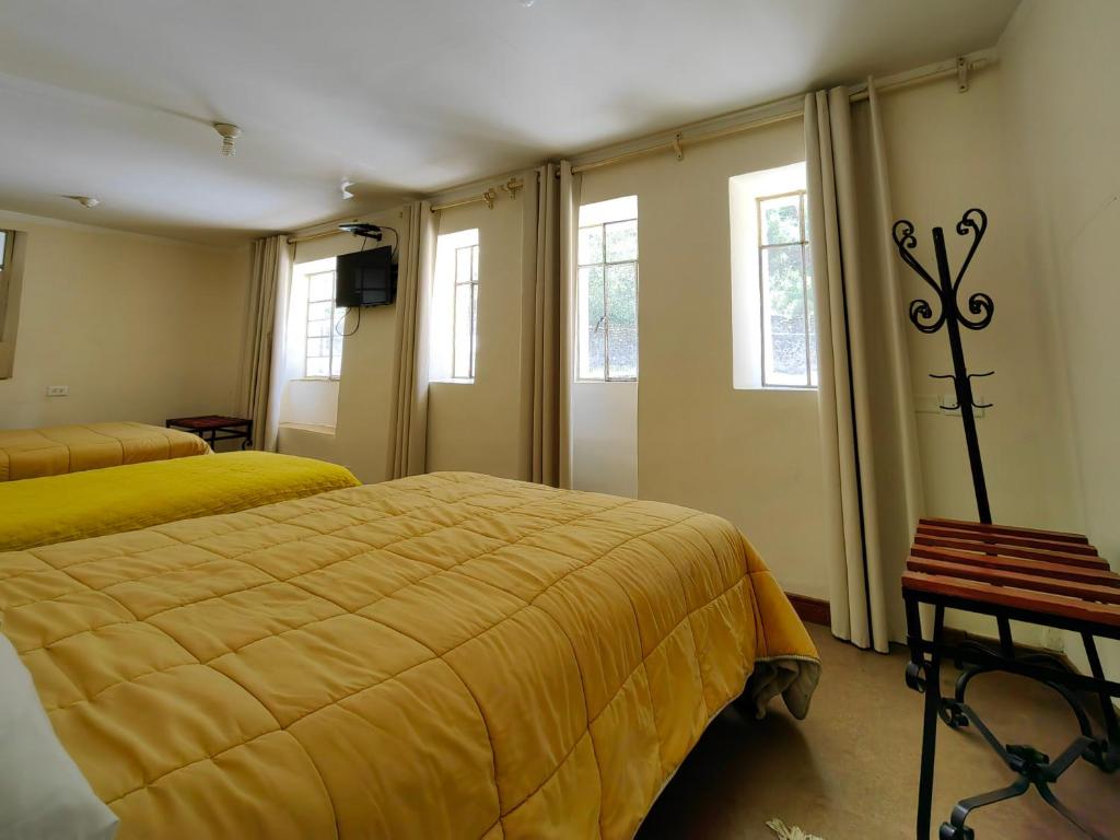 1 dormitorio con 2 camas, sábanas amarillas y ventanas en Centro Cusco Inti en Cuzco