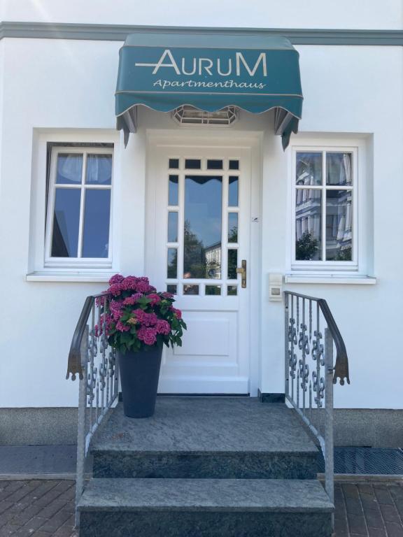 a front door of a white house with a potted plant at Apartmenthaus Aurum in Ahlbeck