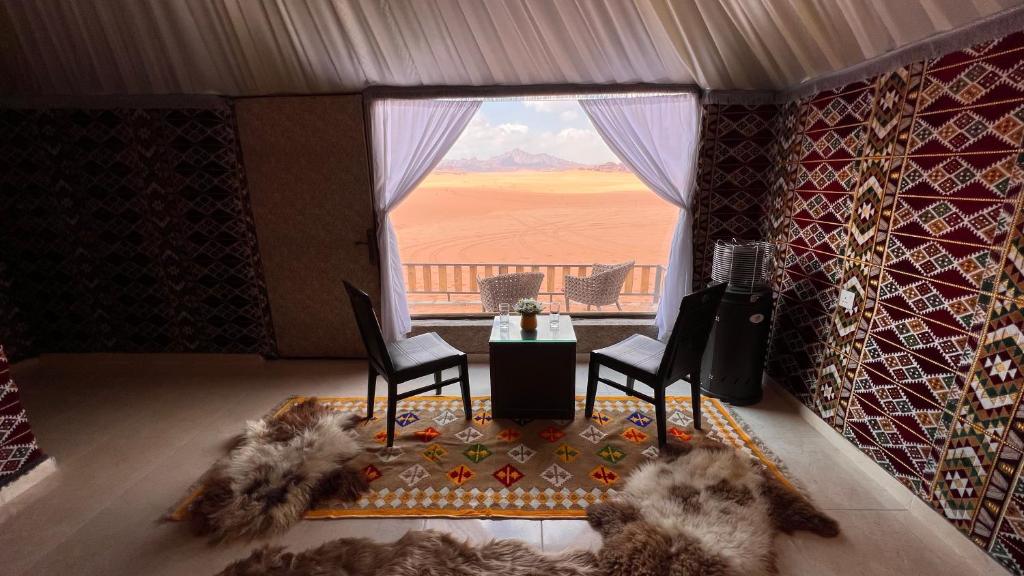 Pokój ze stołem i krzesłami oraz dużym oknem w obiekcie Rum Crown w mieście Wadi Rum