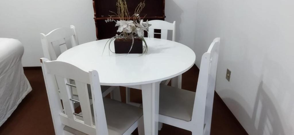 einen weißen Tisch und Stühle mit Vase drauf in der Unterkunft Praça Residence in Uruguaiana