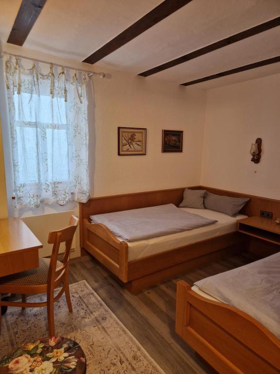a bedroom with two beds and a table and a desk at Brunnenputzer Pension Restaurant in Külsheim