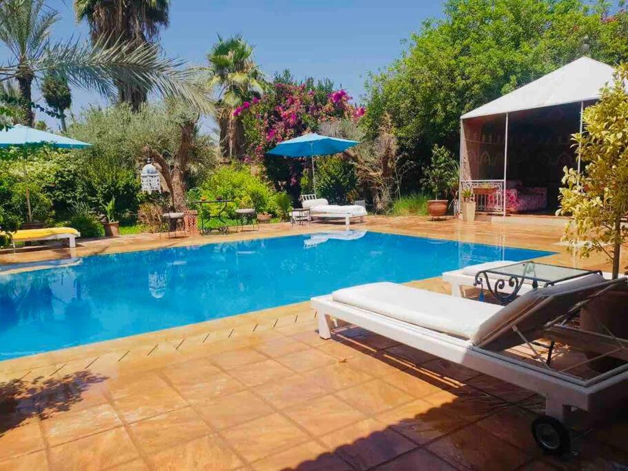 a pool with a bed and an umbrella at Villa avec piscine in Marrakech