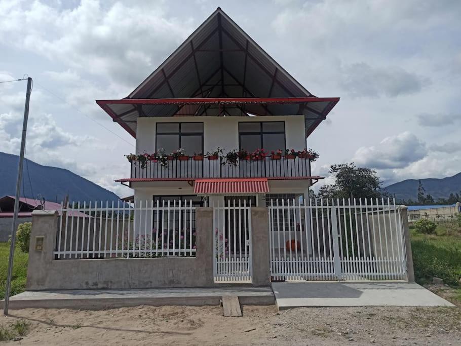 a small house with a white fence in front of it at Hermosa y espléndida casa en Oxapampa in Oxapampa