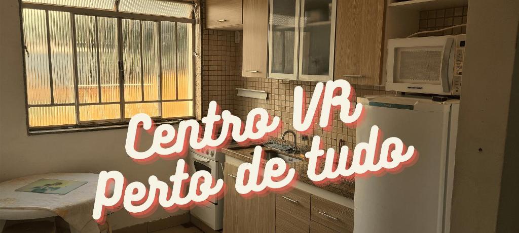 a kitchen with a white refrigerator and a sign that says centre mi gotta tie up at Apt(2) no centro de VR tudo perto até 7 pessoas in Volta Redonda