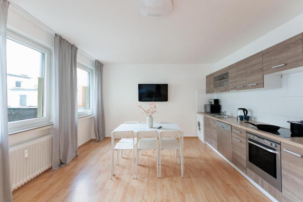 una cucina bianca con tavolo e sedie di T&K Apartments - 3 Room Apartment a Mülheim an der Ruhr