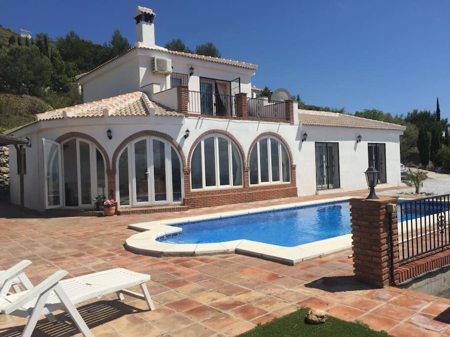 een huis met een zwembad ervoor bij Casa Delfin: Luxurious villa with heated pool & mountain views in Cómpeta