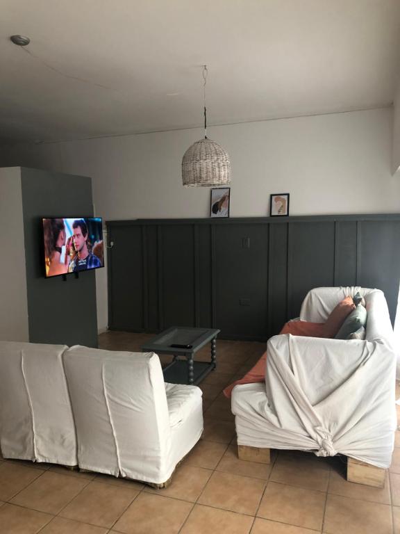 a living room with two white couches and a tv at Dpto Pque in Azul