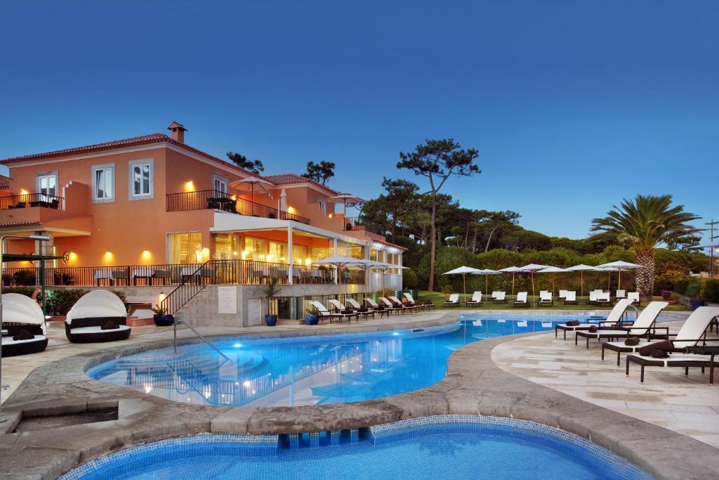 a resort with a swimming pool with chairs and a building at Senhora da Guia Cascais Boutique Hotel in Cascais