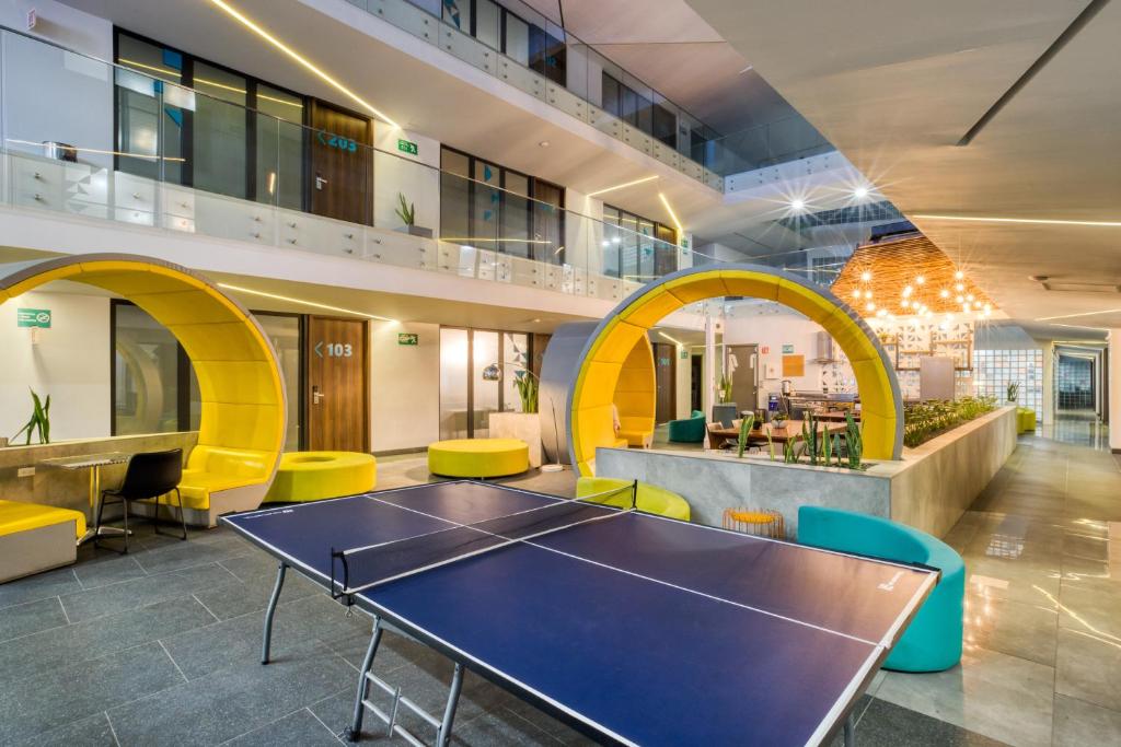 an office with a ping pong table and yellow chairs at Eazy Rio by ULIV in Tijuana