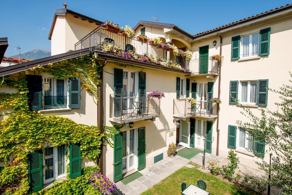 een appartementengebouw met groene luiken en bloemen op de balkons bij Residence la Limonera in Bellagio