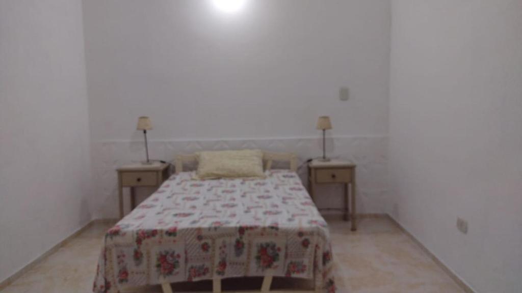 a bedroom with a bed with two nightstands and two tables at HERMOSA CASONA ANTIGUA Y LUMINOSA in Villa María