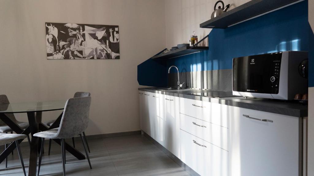 uma cozinha com armários brancos e uma mesa com um micro-ondas em Etna Suite Design Apartments em Catânia