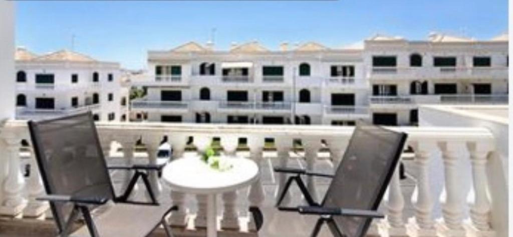 una mesa blanca y sillas en un balcón con edificios en Apartment Moni Cabanas de Tavira Algarve, en Cabanas de Tavira