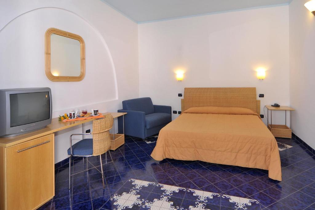 a bedroom with a bed and a tv and a chair at Hotel Aura in Vulcano