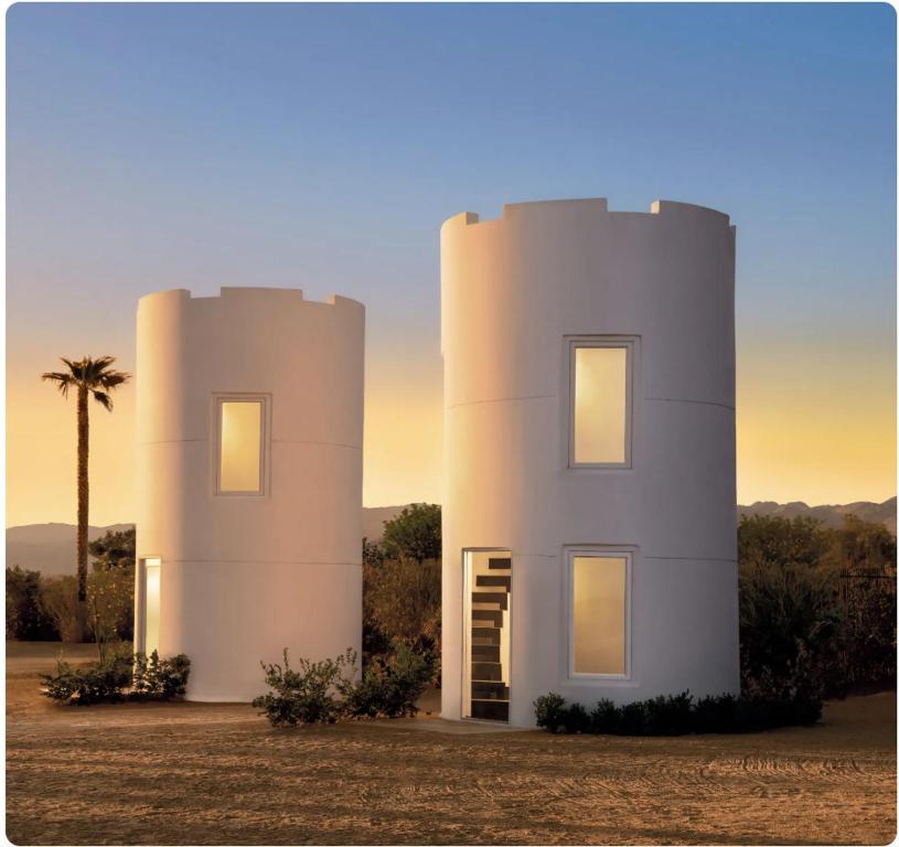 a white house with a palm tree in front of it at The Castle House Estate in Joshua Tree