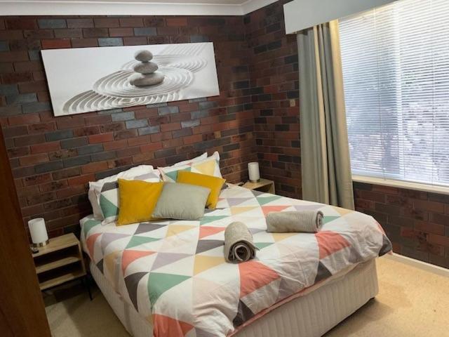 ein Schlafzimmer mit einem großen Bett mit Ziegelwand in der Unterkunft Wynyardway in Tumut