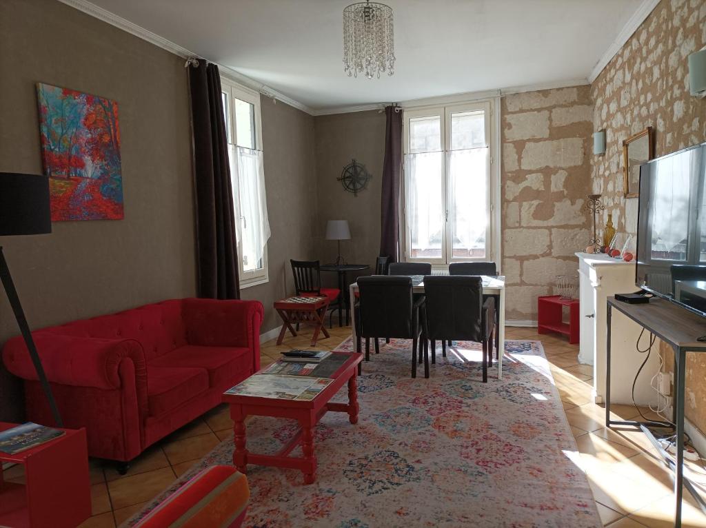 a living room with a red couch and a table at La Boussole - Maison meublée 3 chambres 6 pers. in Chinon
