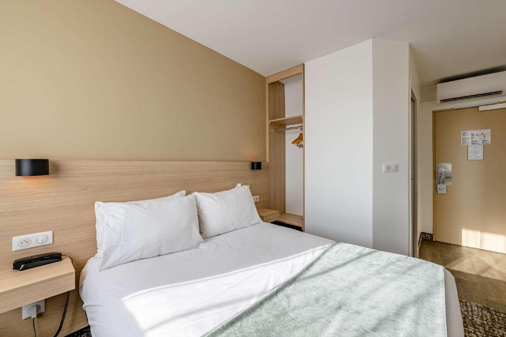 1 dormitorio con cama blanca y cabecero de madera en Sure Hotel by Best Western Bordeaux Lac, en Burdeos