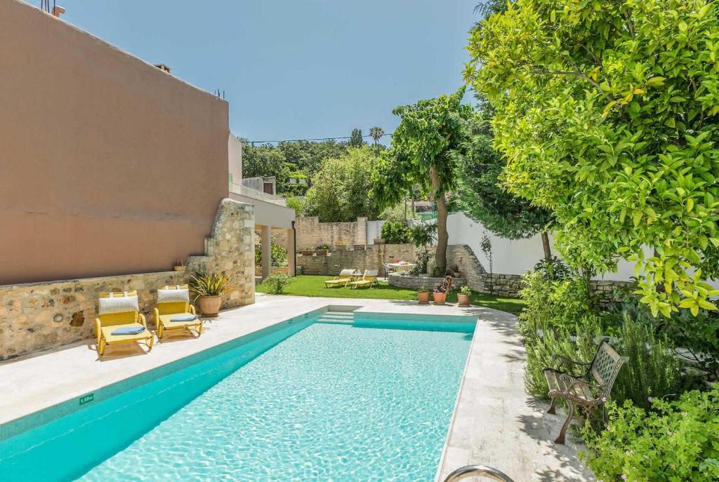 a swimming pool in a yard with two chairs and a house at Villa Verde in Arménoi