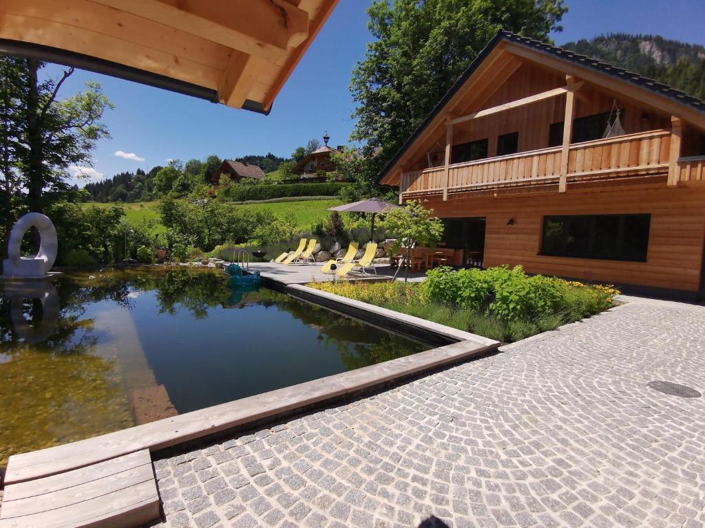 a house with a swimming pool next to a building at Luxury chalet in Tauplitz Styria with sauna and swimming pond in Bad Mitterndorf