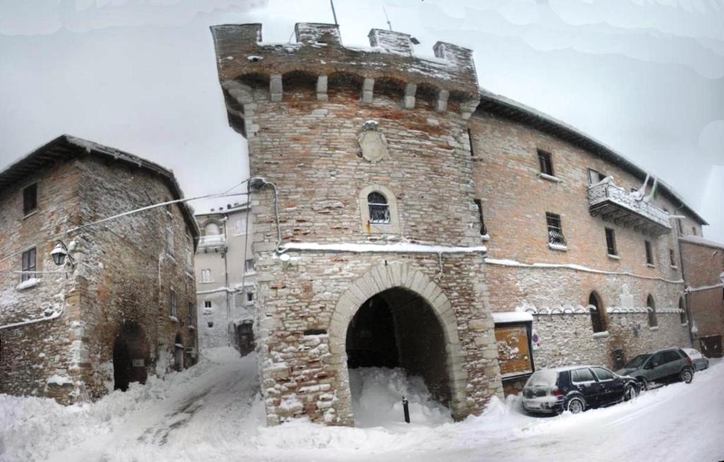 Fossato di VicoにあるAppartamento nel Castello presso Gubbioの雪塔のある大きなレンガ造りの建物