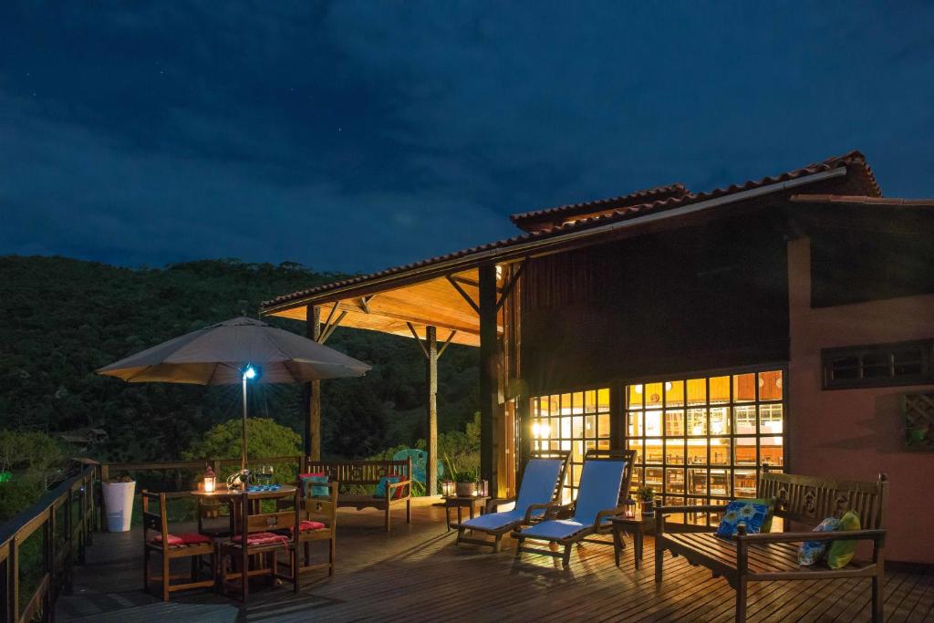 eine Terrasse mit Stühlen, Tischen und einem Sonnenschirm in der Unterkunft Pousada do Morro Verde in Carvalhos