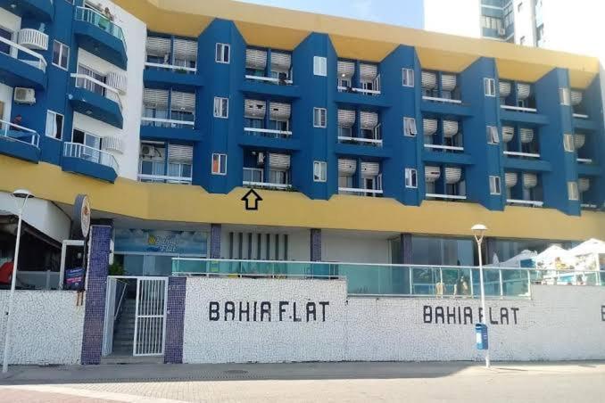 un edificio azul y amarillo con un cartel delante en Bahia Flat localização excelente, en Salvador