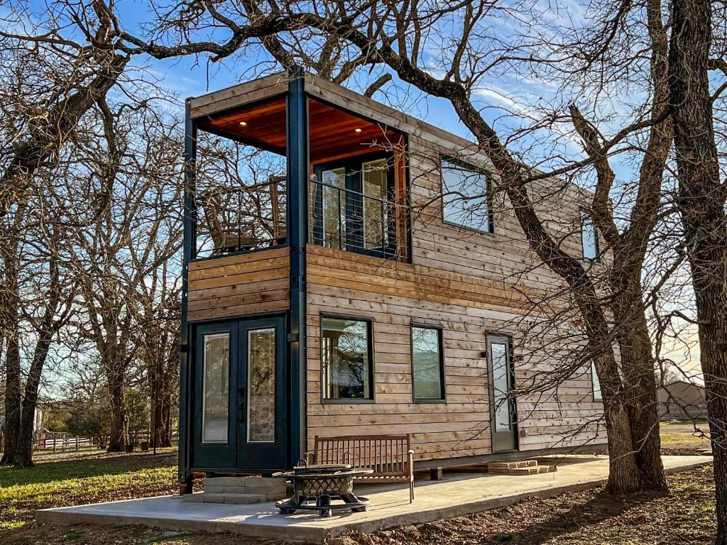 a tiny house with a bench in front of a tree at NEW The Flagship 2 Story Container Home in Waco