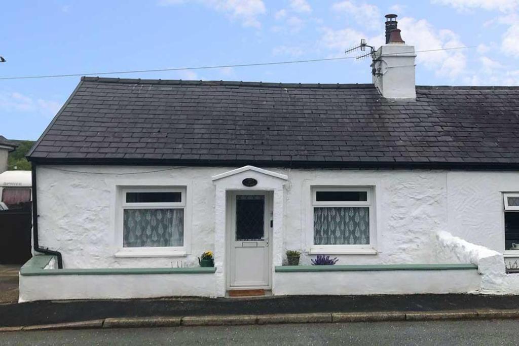 Casa blanca con puerta y ventanas blancas en Cobweb Cottage en Waenfawr