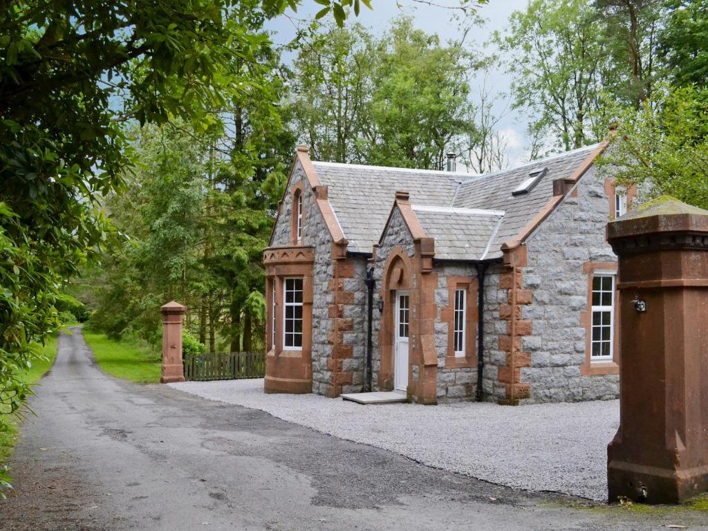 uma pequena casa de pedra com uma entrada em Barncailzie Lodge em Kirkpatrick Durham