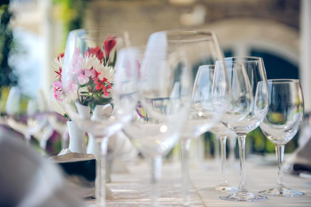 a row of wine glasses on a table with flowers at Hotel Azimut in Sveti Stefan