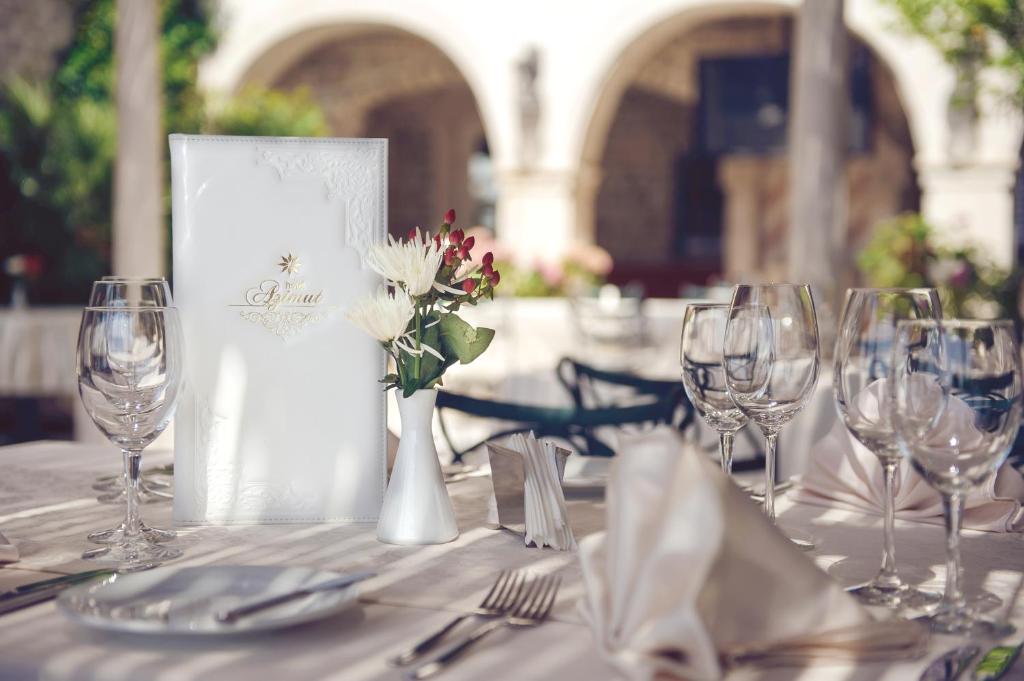 a table with glasses and a vase with flowers on it at Hotel Azimut in Sveti Stefan