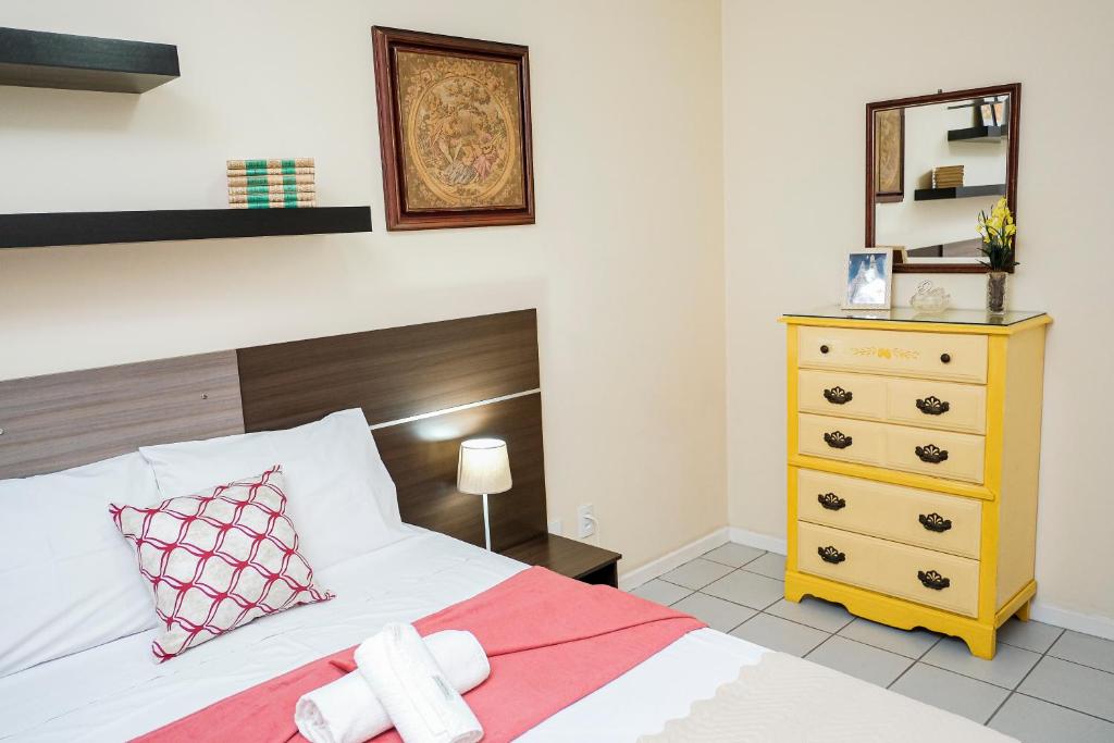 een slaapkamer met een bed en een gele dressoir bij Praia da Costa 2 Quartos com Suite Clássico in Vila Velha