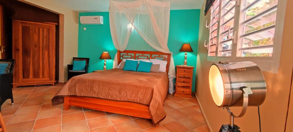 Un dormitorio con una cama con paredes verdes y una ventana en T1 D'ALICE SAINTE ANNE CENTRE, en Sainte-Anne