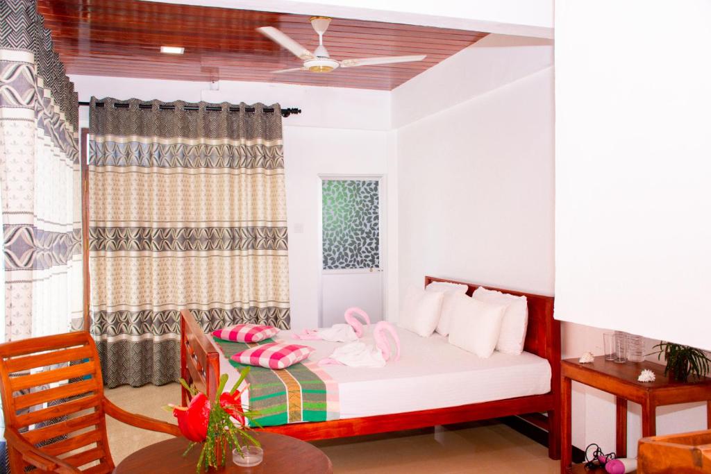 Un dormitorio con una cama con almohadas rosas y una mesa. en Coconut Cove Lodge, en Tangalle