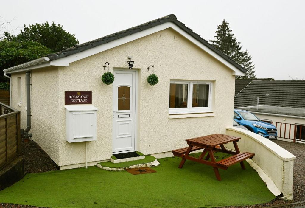 una pequeña casa con una mesa de picnic delante de ella en Rosewood Cottage en Fort William