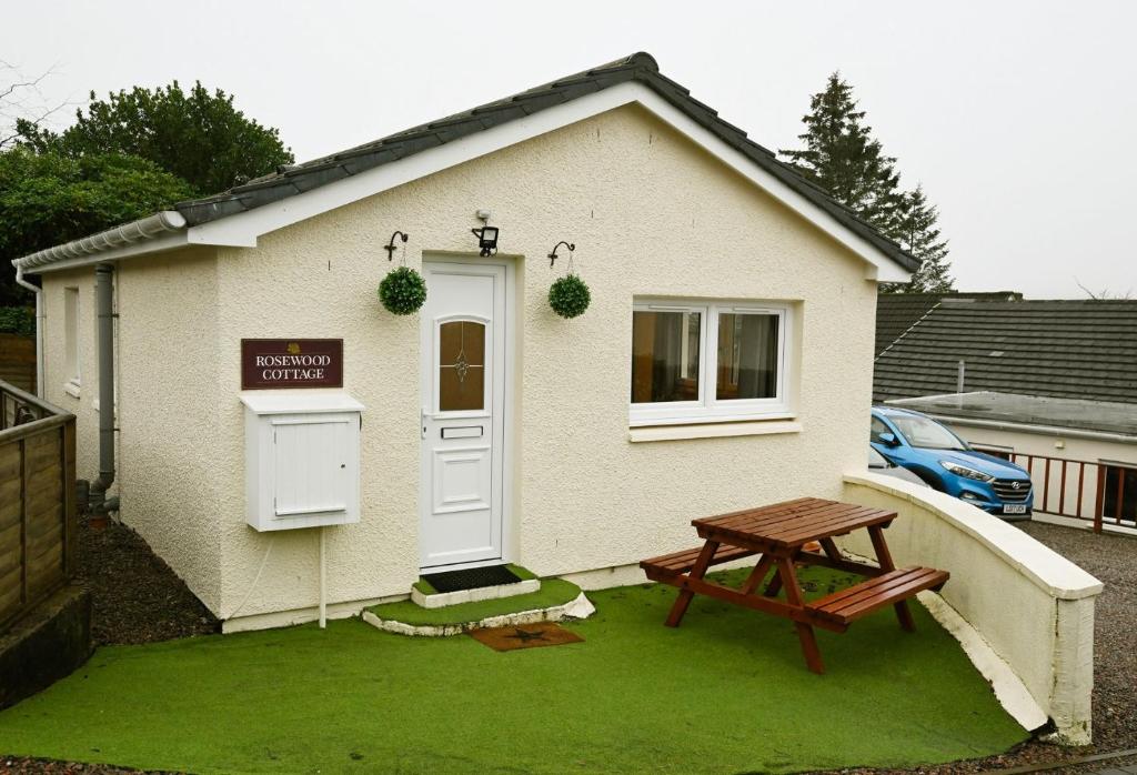 ein kleines Haus mit einem Picknicktisch davor in der Unterkunft Rosewood Cottage in Fort William