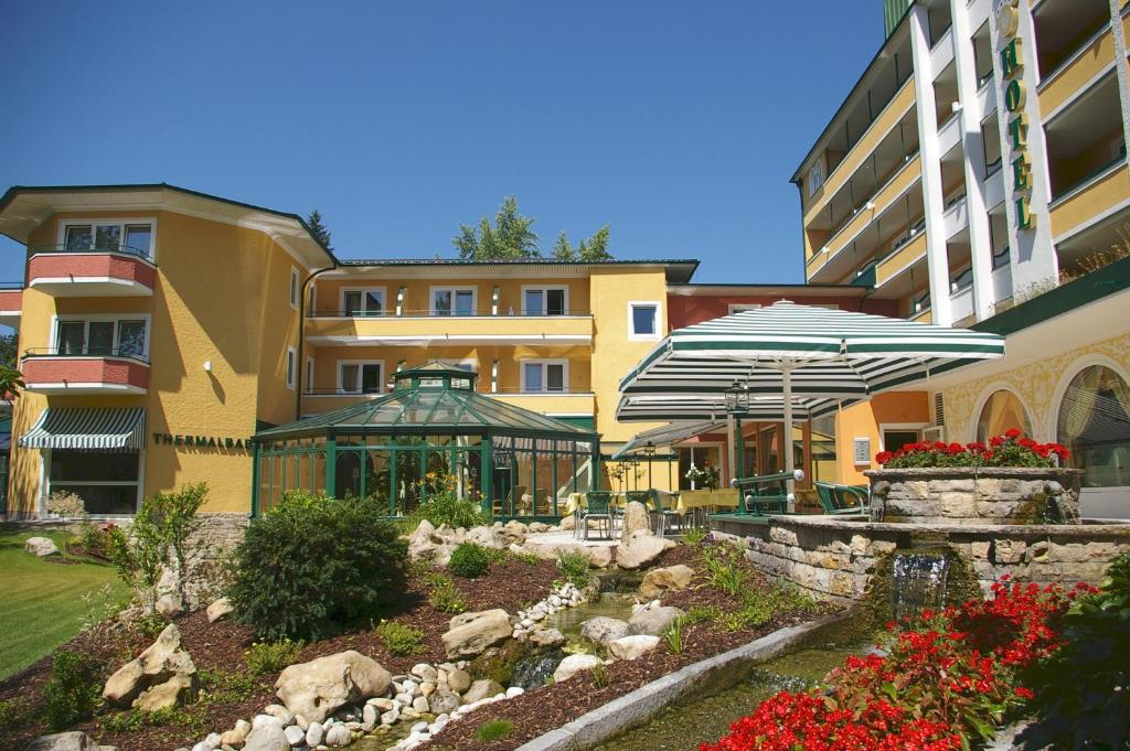 ein Gebäude mit einem Garten mit Sonnenschirmen davor in der Unterkunft Parkhotel in Bad Füssing