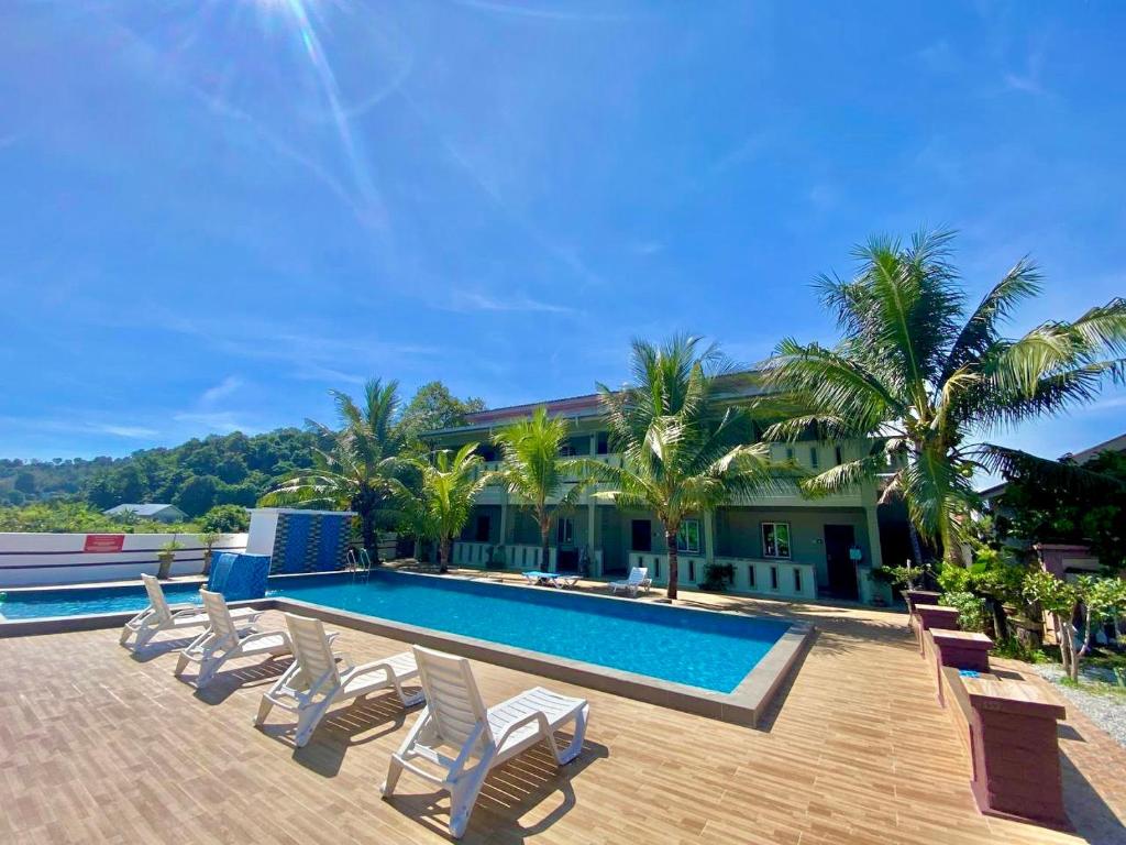 - une piscine avec des chaises longues et des palmiers dans l'établissement Cenang Room Rahsia Motel, à Pantai Cenang